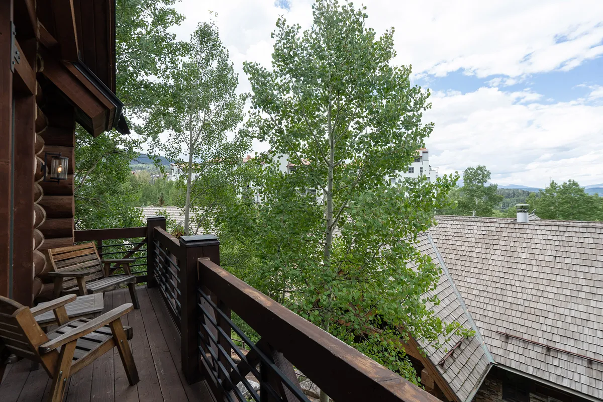 A tranquil mountain balcony with wooden chairs, aspen trees, and distant mountain views, perfect for sipping coffee or unwinding while enjoying the fresh air and gentle breezes. The scene evokes peace and connection to the outdoors.